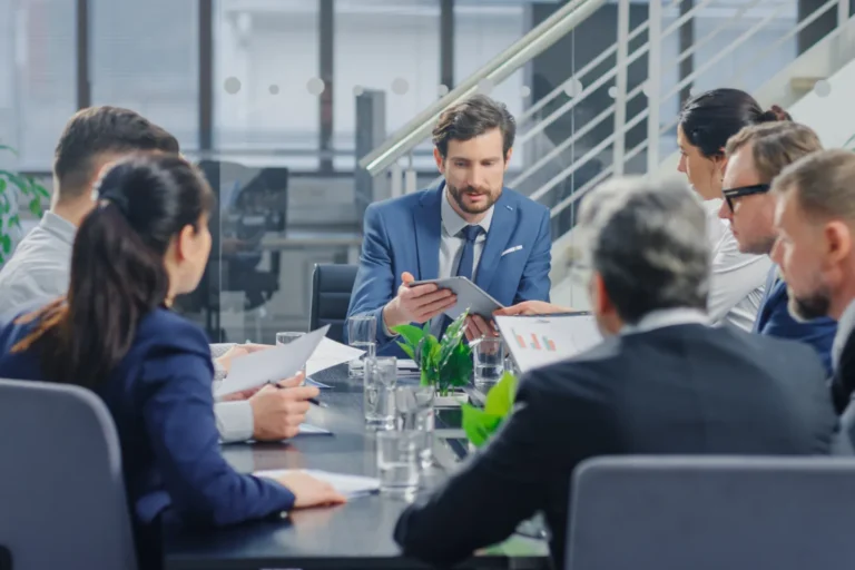 Sei manager riuniti intorno a un tavolo mentre fanno riunione in un ufficio moderno